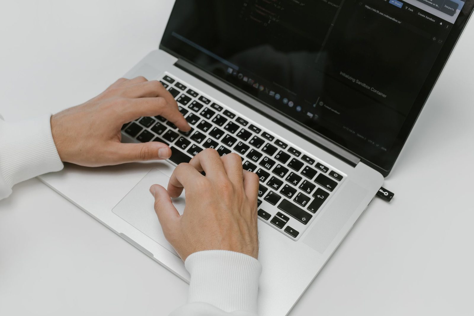 Mains d'une personne tapant sur le clavier d'un ordinateur portable posé sur un bureau blanc