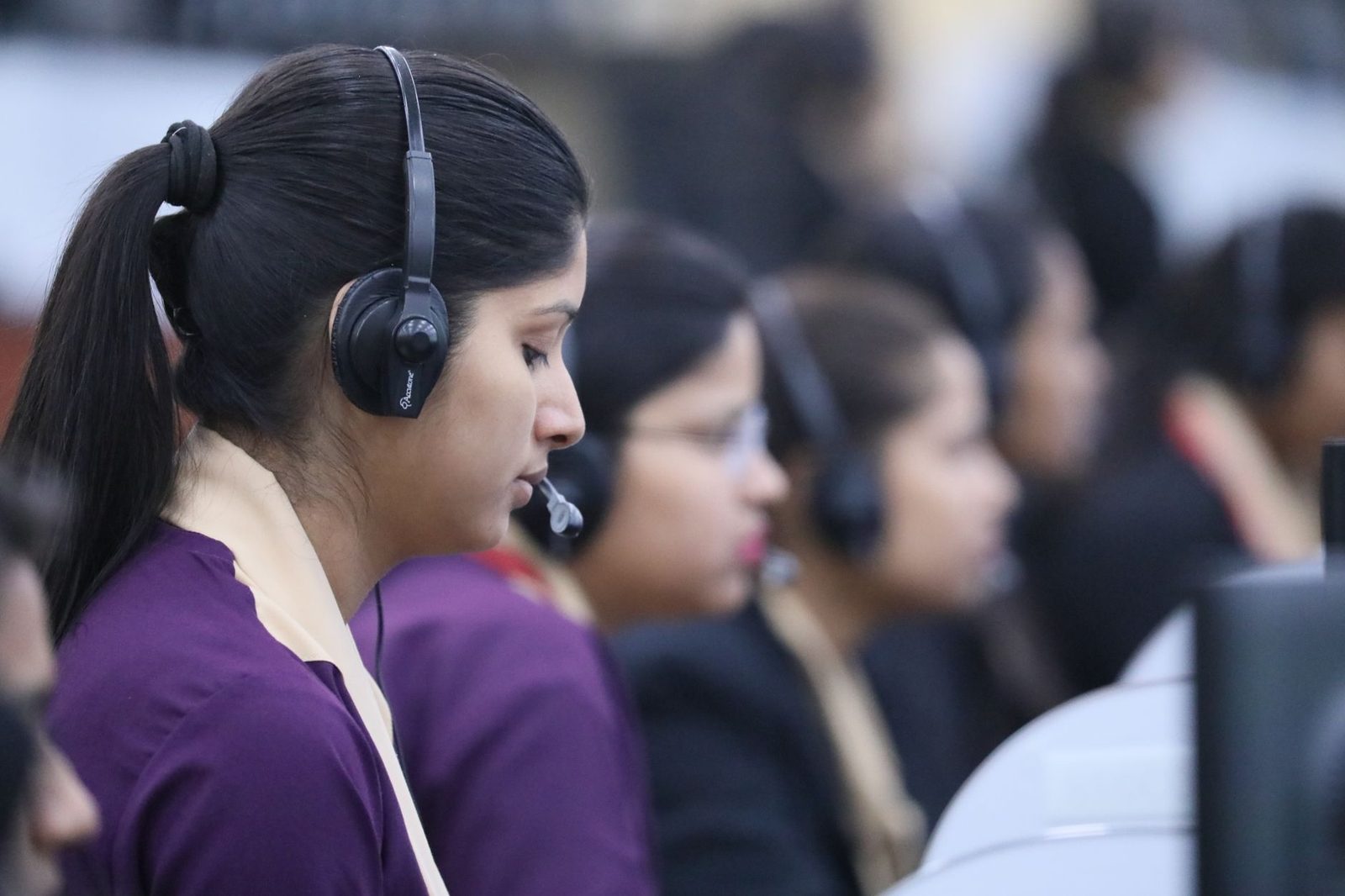 Téléconseillères avec casques micro alignées devant des écrans dans un centre d'appels