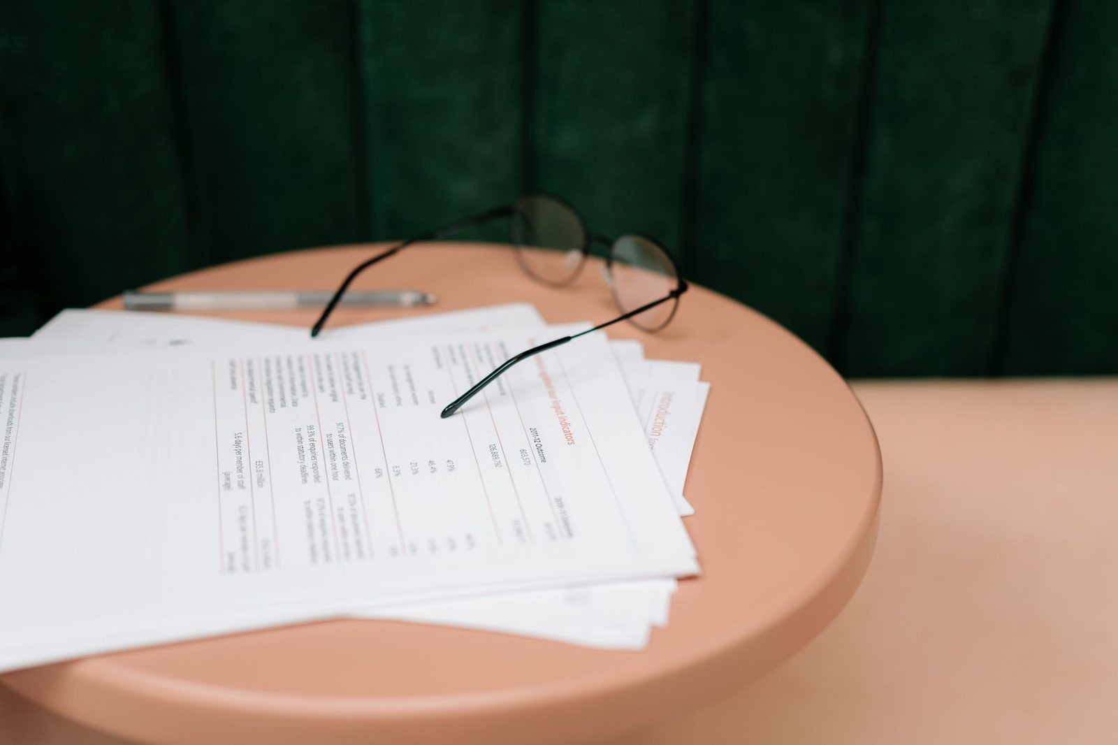 Documents administratifs imprimés, stylo et lunettes posés sur une table ronde