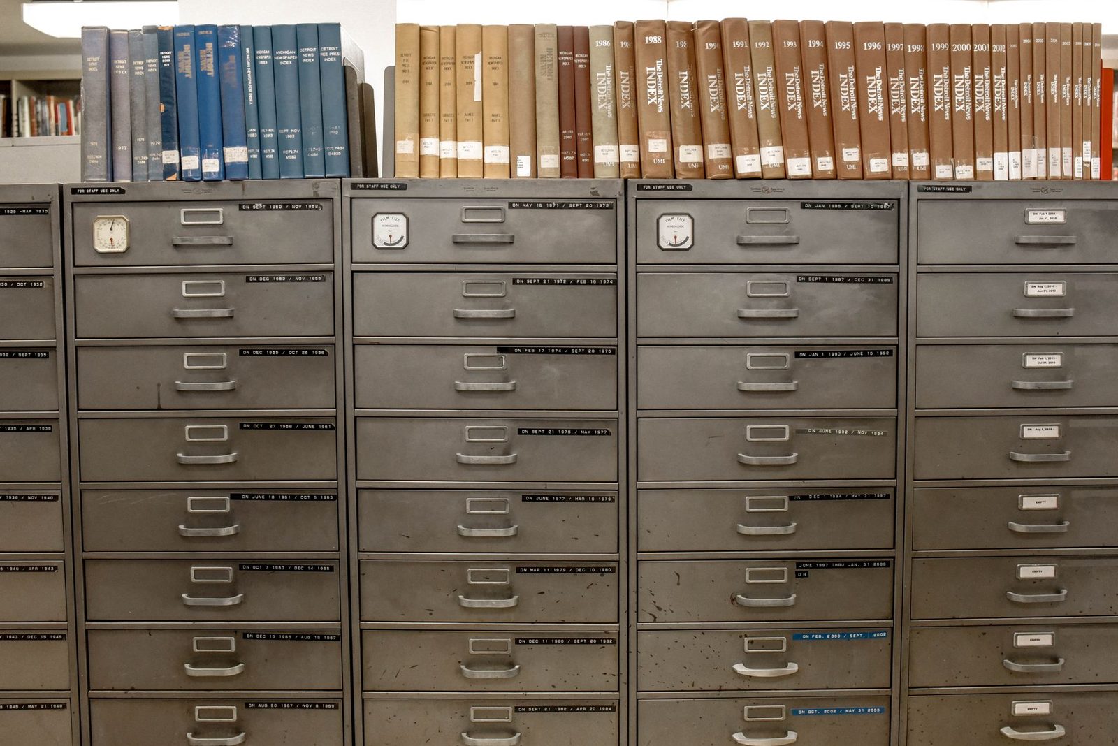 Meubles à tiroirs métalliques d'archives étiquetés par dates, surmontés de registres et index reliés