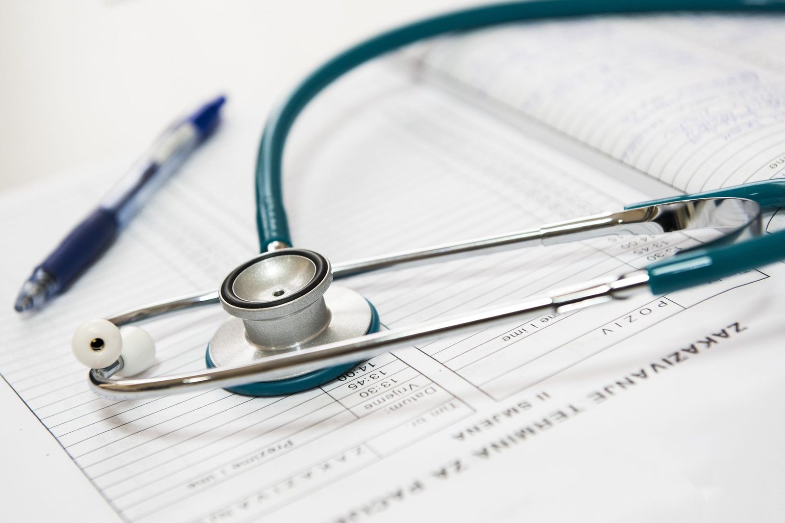 Stéthoscope vert et stylo posés sur des formulaires médicaux imprimés