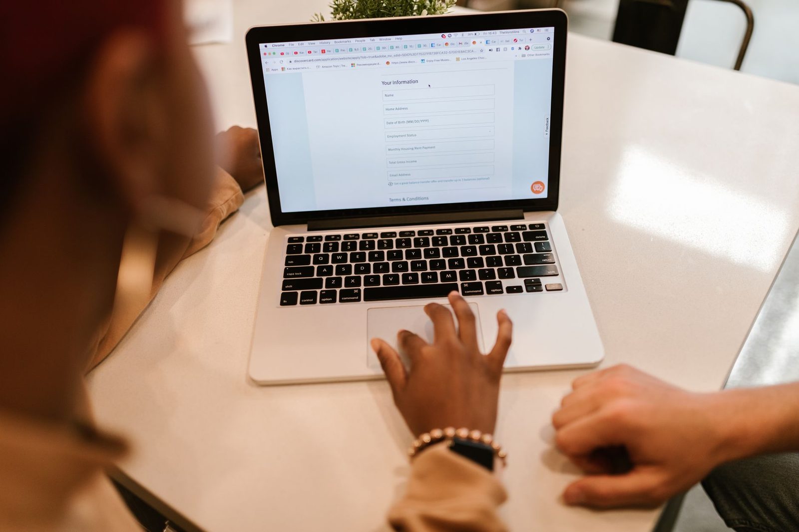 Personne remplissant un formulaire en ligne sur un ordinateur portable posé sur une table blanche